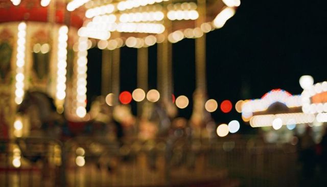Spinning illuminated carousel with blurred riders and colorful bokeh lights at night fair