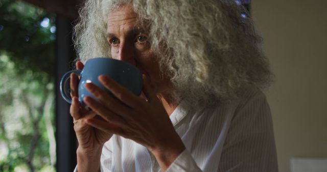 Senior Woman with Gray Hair Drinking from Blue Mug at Home - Download Free Stock Images Pikwizard.com