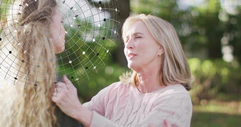 Woman in pink sweater comforting companion in garden with netted headpiece