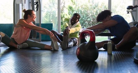 Friends stretching together in gym for post-workout relaxation