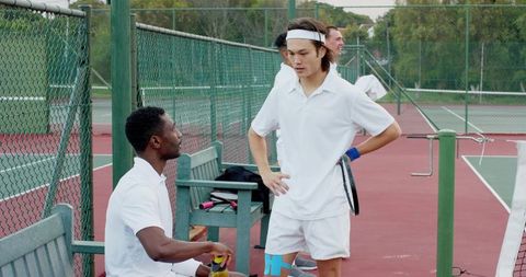 Tennis players discussing match courtside on outdoor hard court team coaching moment