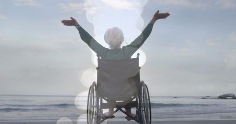 Joyful Senior Woman in Wheelchair Celebrating Freedom by Ocean