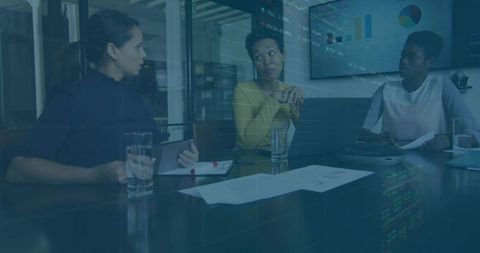 Diverse female team collaborating around conference table reviewing analytics charts