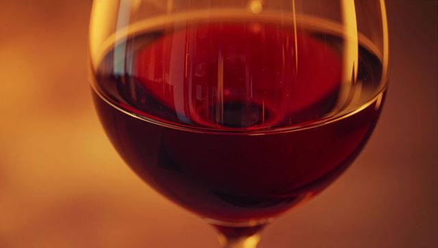 Elegant glass of red wine reflecting warm ambient light