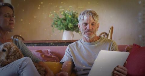 Mature couple relaxing on sofa with tablet and dog cozy living room evening and warmth