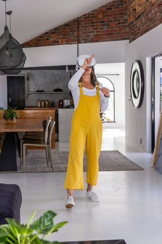 Woman wearing vr headset exploring virtual space in bright modern open-plan home interior