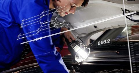Automotive technician inspecting engine with worklight and diagnostic HUD overlay