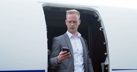 Confident Businessman Exiting Private Jet and Using Smartphone - Download Free Stock Images Pikwizard.com