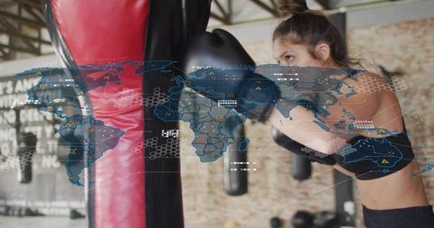 Female boxer punching heavy bag with holographic world map overlay for global training