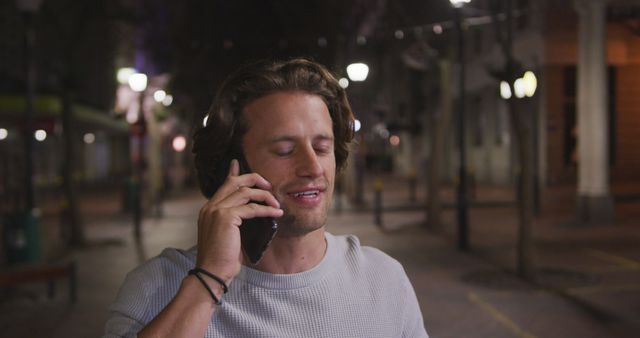 Young Man Smiling While Talking on Phone in Nighttime Urban Setting - Download Free Stock Images Pikwizard.com