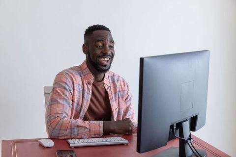 Smiling african american man working at home office on computer