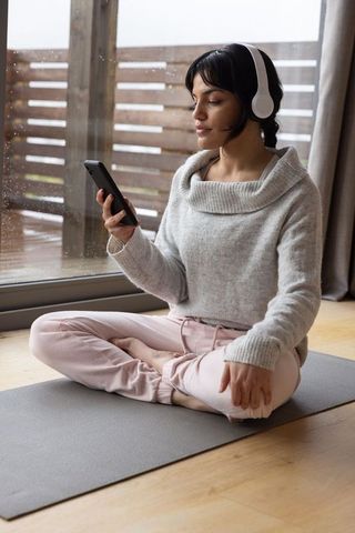 Woman in Cozy Home Setting Listening Indoors on Yoga Mat