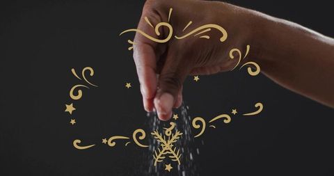 Right hand pinching and sprinkling fine salt with gold ornamental swirls, dramatic closeup