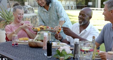 Diverse Friends Enjoying Outdoor Meal with Fresh Skewers