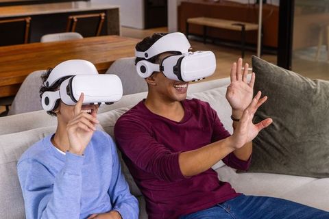 Excited Friends Interacting with Virtual Reality Headsets on Sofa