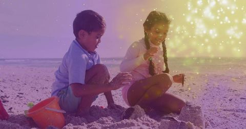 Children building sandcastles at beach with magical glow