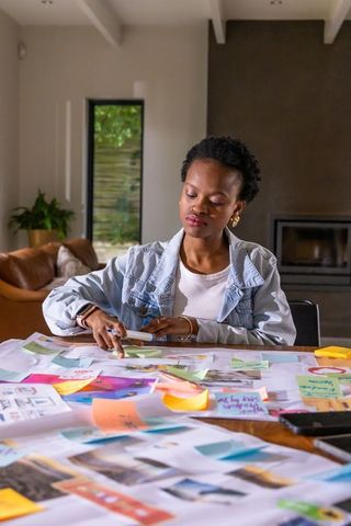 African american woman creating colorful moodboard and planning project in home workspace