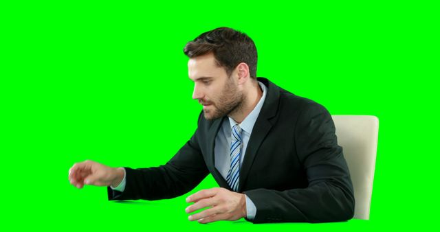 This image features a businessman wearing a suit and tie using an invisible digital tablet against a green screen backdrop. Useful for presentations, video editing projects requiring chroma keying, or advertisements focusing on digital or business concepts.
