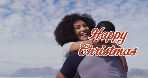 Diverse Couple Embracing on Beach with Christmas Greeting