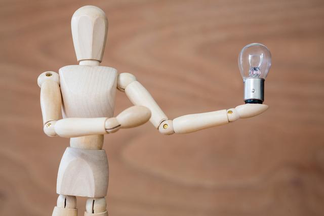 Conceptual image of figurine holding an electric bulb