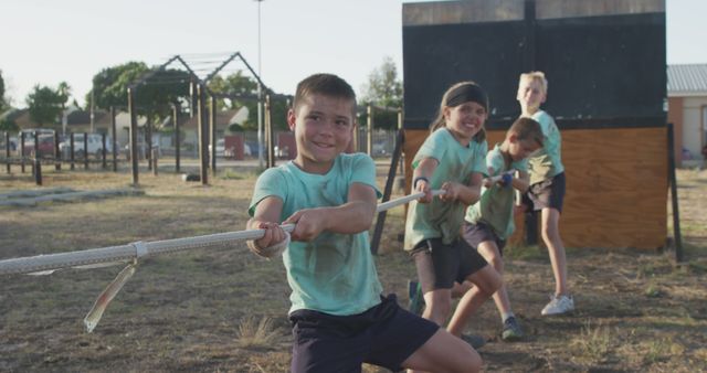 Determined, happy caucasian boys pulling tug of war rope on bootcamp training course. Fitness, childhood, teamwork, challenge and healthy lifestyle.