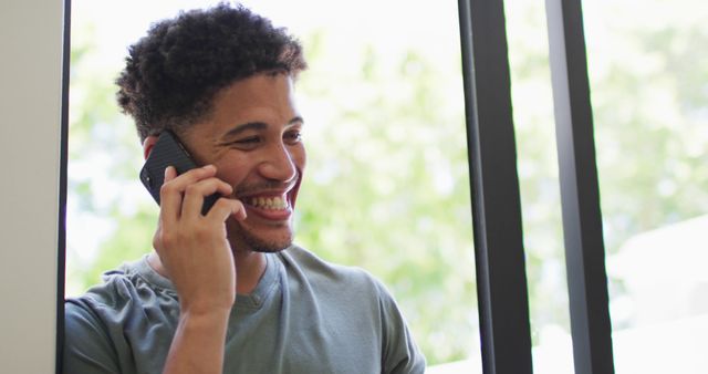 Happy biracial man talking on smartphone and smiling. domestic lifestyle, spending free time at home.