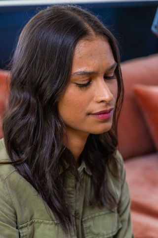 Contemplative african american woman on rust sofa wearing olive shirt, serene closeup portrait