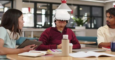 African American coworker testing VR headset while teammates collaborating in modern workspace