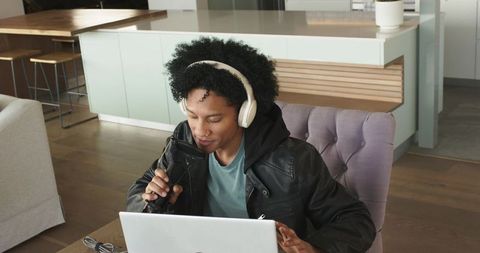 African american creator recording podcast at home workspace with headphones and laptop