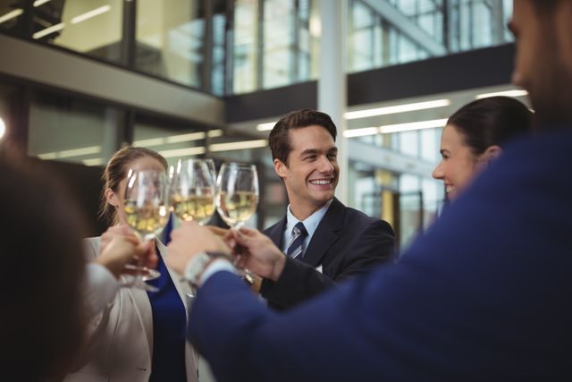 Business professionals toasting glasses of champagne in a modern office environment. Ideal for illustrating corporate celebrations, team achievements, business success, and professional gatherings. Suitable for use in business blogs, corporate websites, and promotional materials.