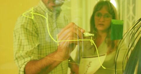 Dynamic Business Team Analyzing Strategies on Transparent Board