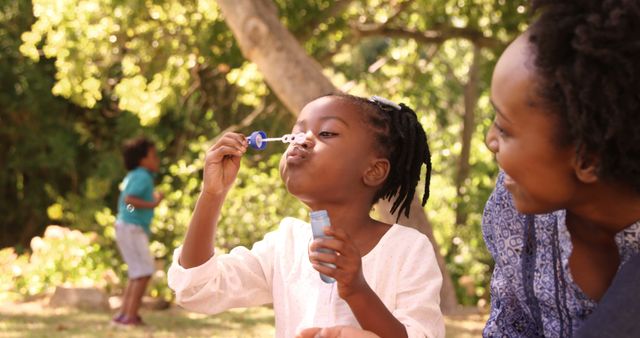 Mother Watching Daughter Blowing Bubbles in Park - Download Free Stock Images Pikwizard.com