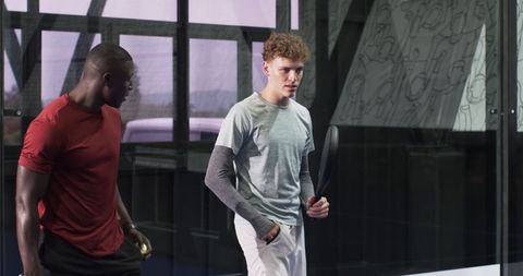 Diverse Male Partners Preparing for Match in Modern Sports Facility