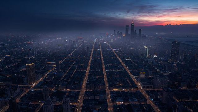 Glowing urban grid leading toward towering skyline at dusk