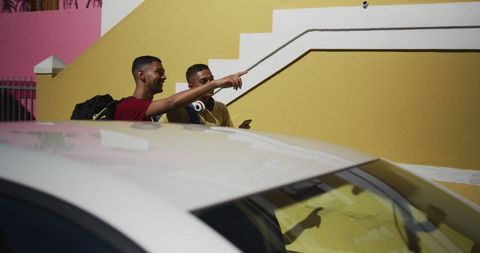 Two Biracial Friends Walking and Using Smartphone on Colorful Street