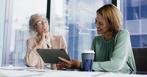 Businesswomen collaborating with tablet in office setting