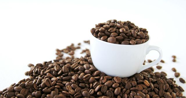 A white cup overflows with brown coffee beans, with copy space. The abundance of beans suggests a deep appreciation for coffee and its rich culture.