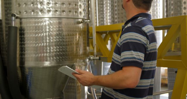 Worker Inspecting Large Stainless Steel Container in Industrial Facility - Download Free Stock Images Pikwizard.com