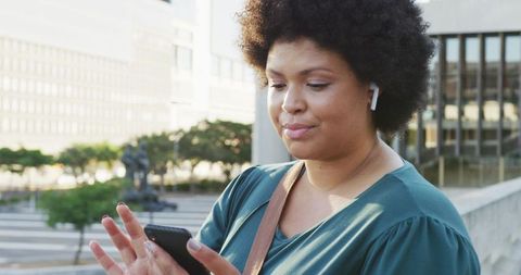 Confident Biracial Woman Enjoying Music on Phone Outdoors