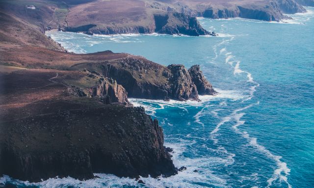 A breathtaking view of coastal cliffs with turquoise water and crashing waves. Perfect for travel blogs, tourism brochures, nature magazines, website backgrounds, and anyone looking to capture the serenity and beauty of a rugged coastline scene.
