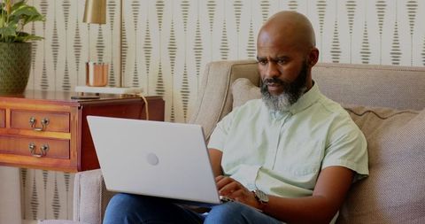 African american man working on laptop in home office setting
