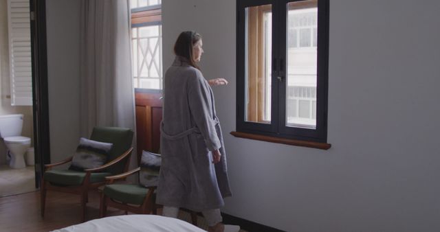 Woman in Robe Looking Out Window in Modern Bedroom - Download Free Stock Images Pikwizard.com