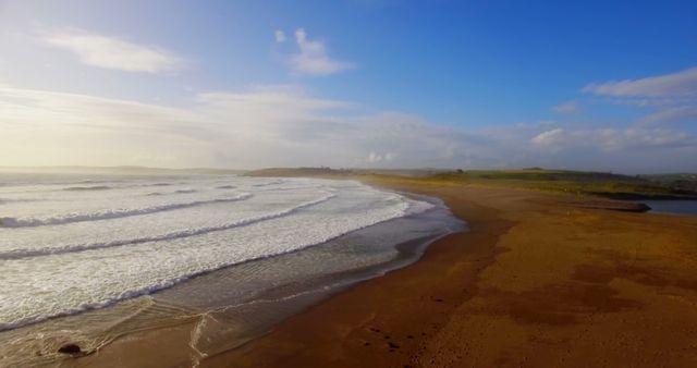 A serene coastal landscape emerges as gentle waves meet a sandy beach under a vast sky. - Download Free Stock Photos Pikwizard.com