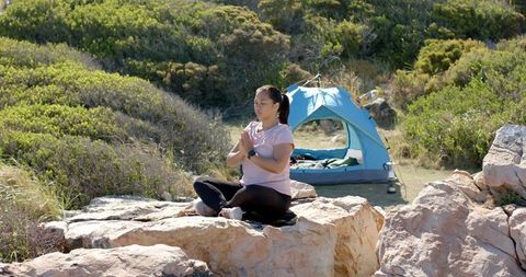 Woman Meditating Outdoors with Tent and Rock Formations
