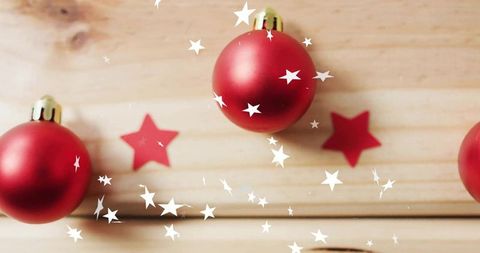 Red christmas baubles and star confetti on rustic wood surface for festive design