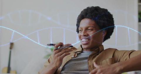 Young man recording voice message on smartphone at home with glowing dna strand overlay