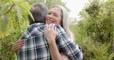 Joyful senior couple hugging outdoors in lush garden