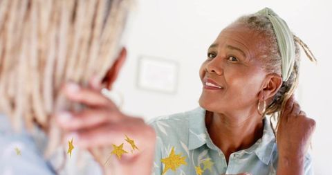 Senior woman adjusting hair at mirror, smiling, wearing headband and hoop earrings