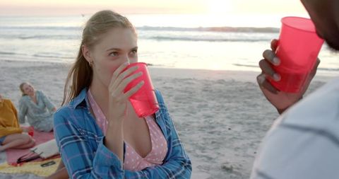 Friends enjoying sunset beach party with red cups