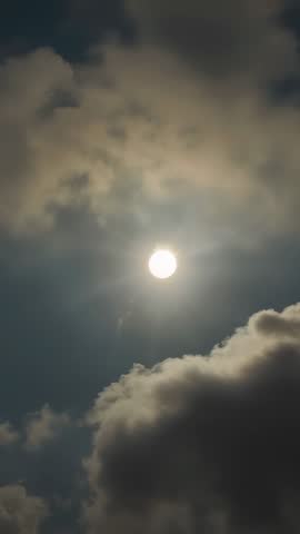 Vertical video of sun shining through drifting cumulus clouds, moody sky time-lapse